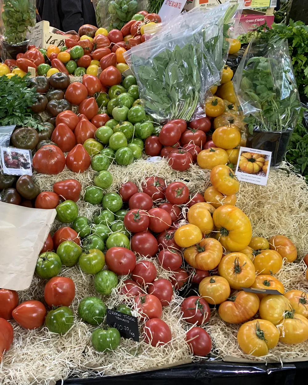 Heirloom tomatoes in red, green and yellow piled high on a market stall
